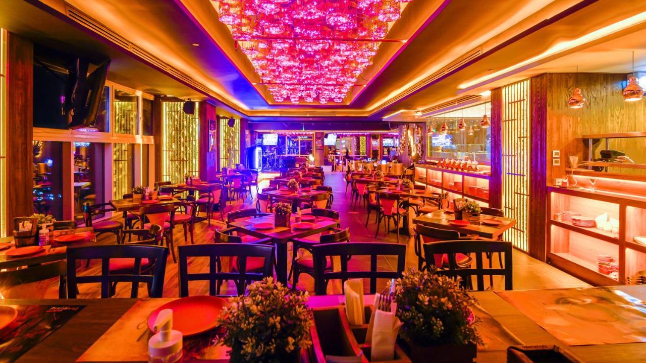 Stella Di Mare Dubai Marina Hotel Exterior foto The photo showcases a vibrant restaurant interior, featuring a lively atmosphere enhanced by colorful lighting. The ceiling is adorned with ornate decorations that emit a warm glow, creating a cozy yet festive ambiance. The dining area is filled with