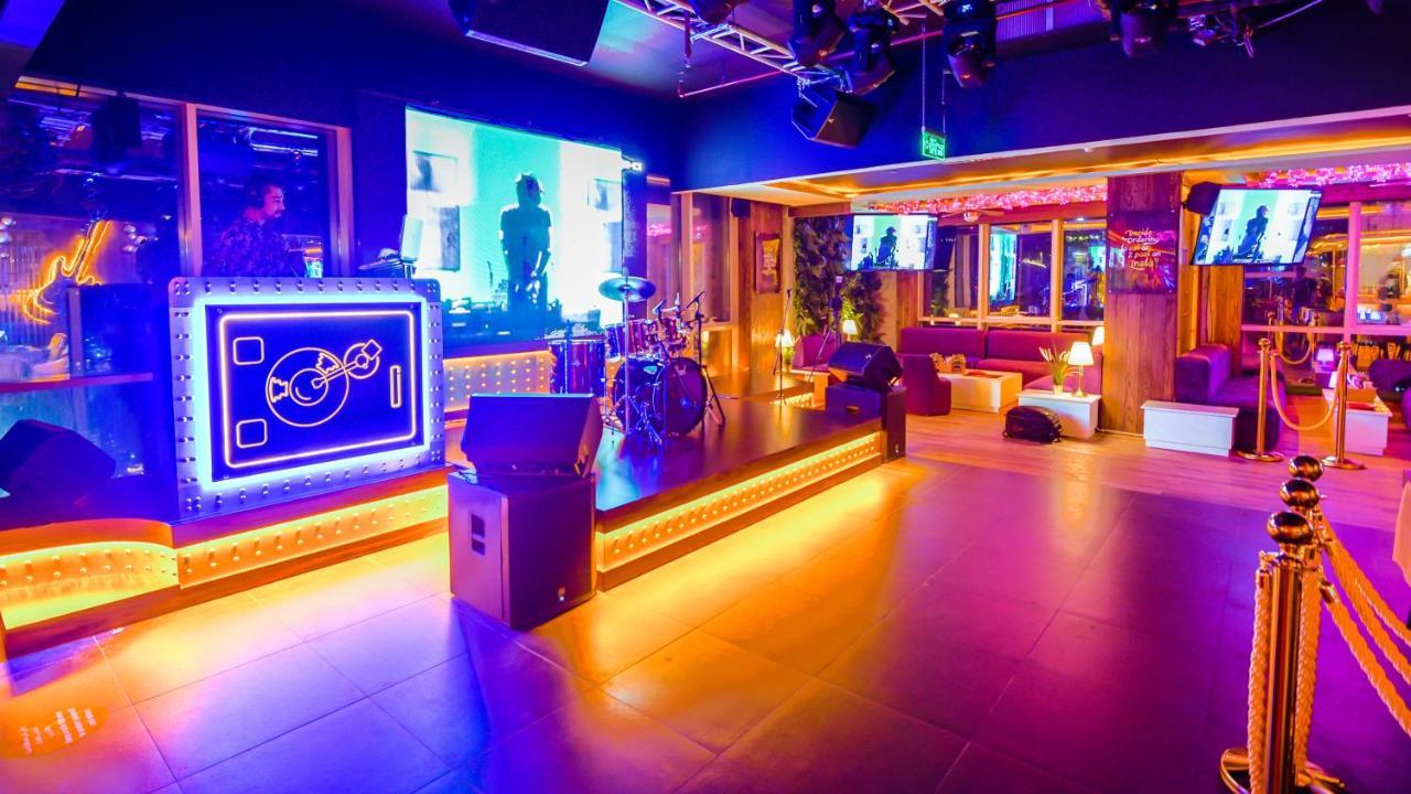Stella Di Mare Dubai Marina Hotel Exterior foto The photo shows a vibrant and modern entertainment venue, possibly a nightclub or live music space. The area features a stage with a set of drums and a DJ booth illuminated by colorful lights, creating an energetic atmosphere. Various screens display