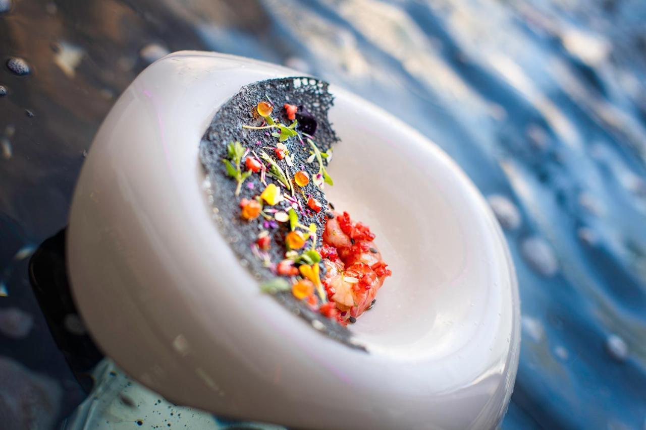 Stella Di Mare Dubai Marina Hotel Exterior foto The photo shows a creatively presented dish that features a circular white plate. On the plate, there is a mound of colorful ingredients, including small bits of meat (likely seafood) and various vibrant garnishes in different colors. The dish appear
